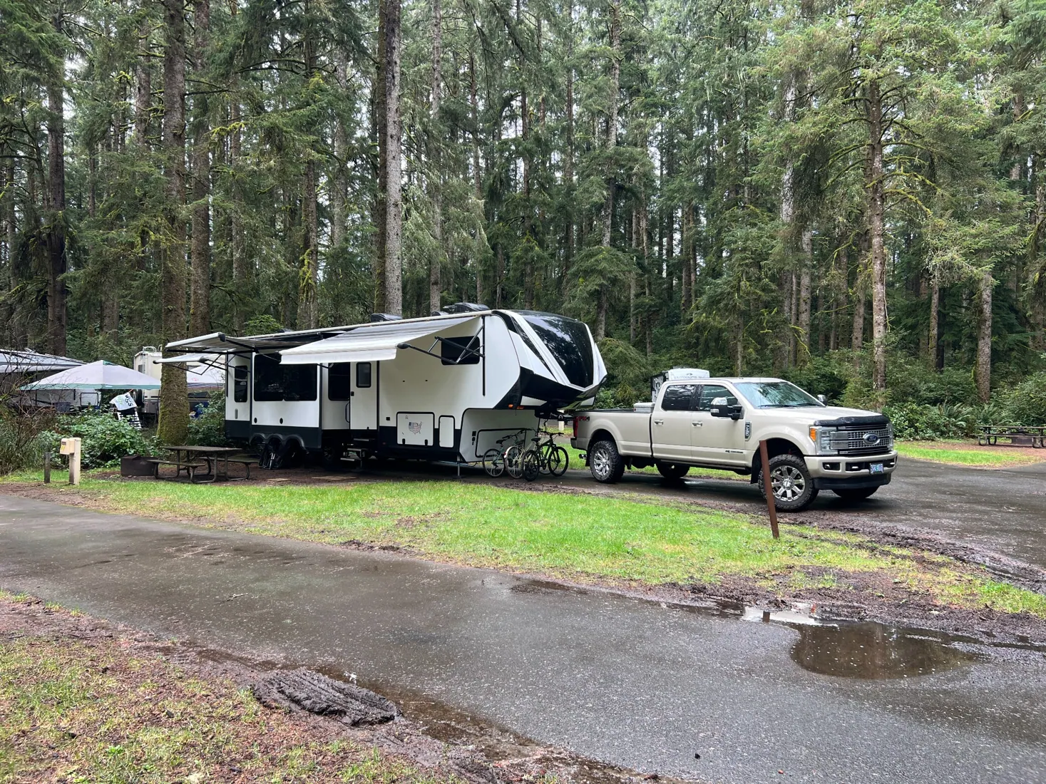 Our Ford F-350 and Grand Design fifth wheel at a wet, wooded campsite in Fort Stevens State Park, Oregon