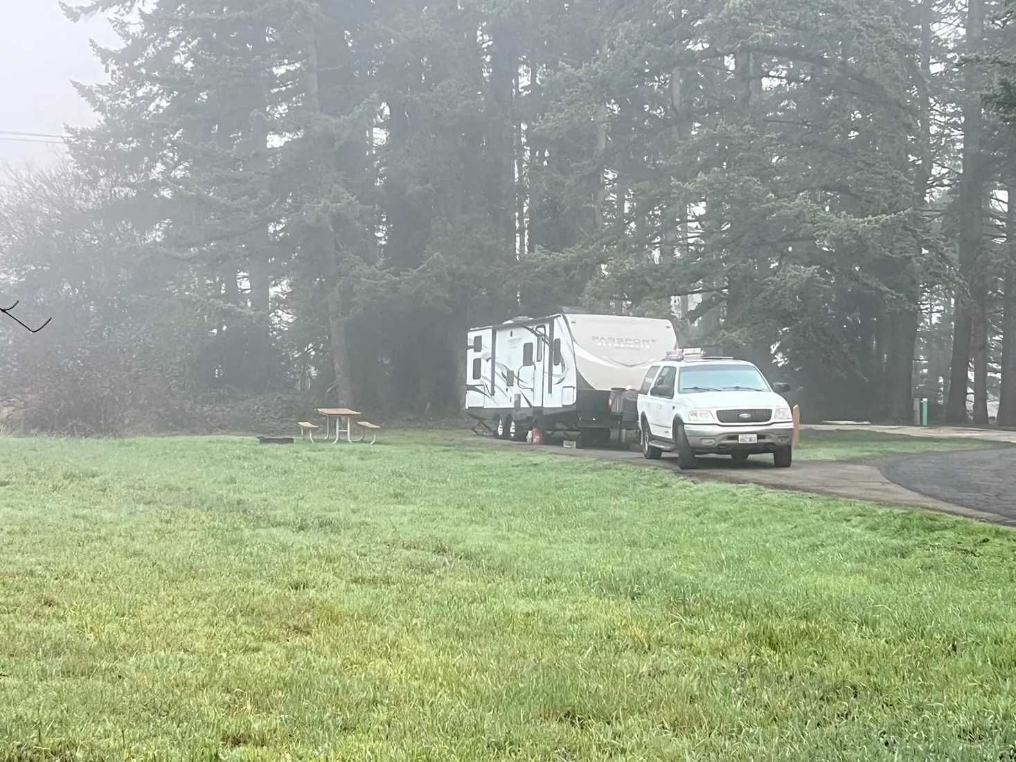 Our Passport travel trailer and Ford Expedition in a misty Pacific Northwest campground